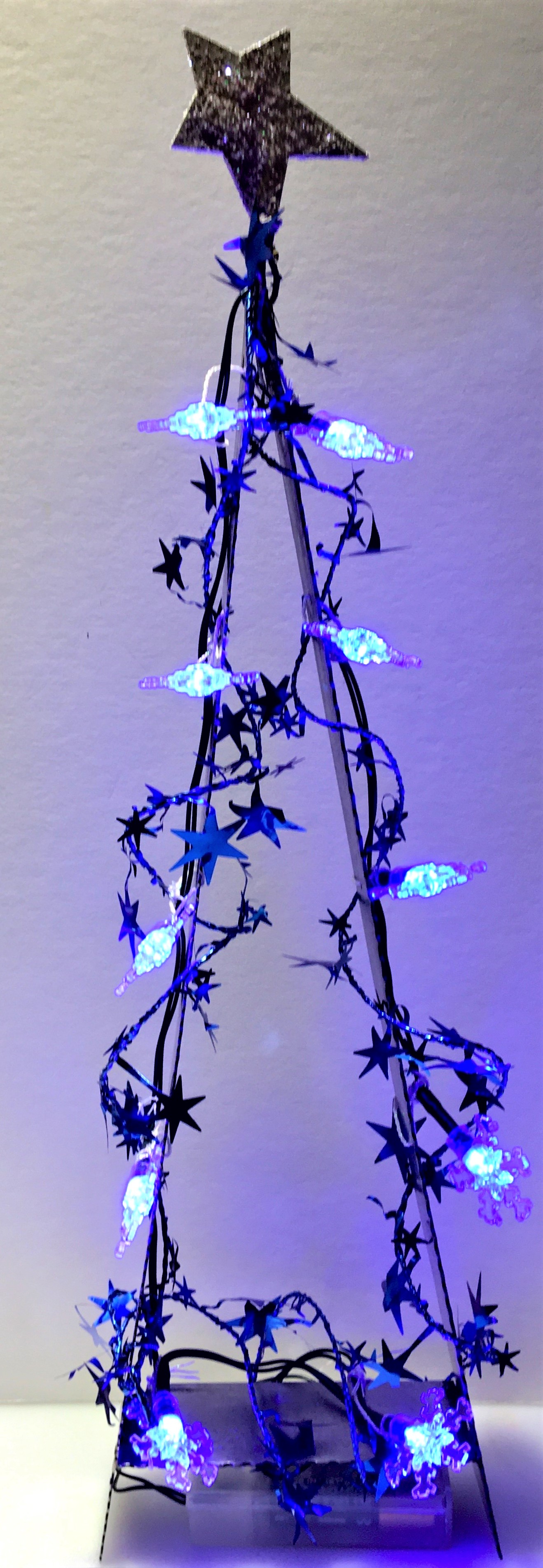 Blue lighted holiday tree with white bulbs and star